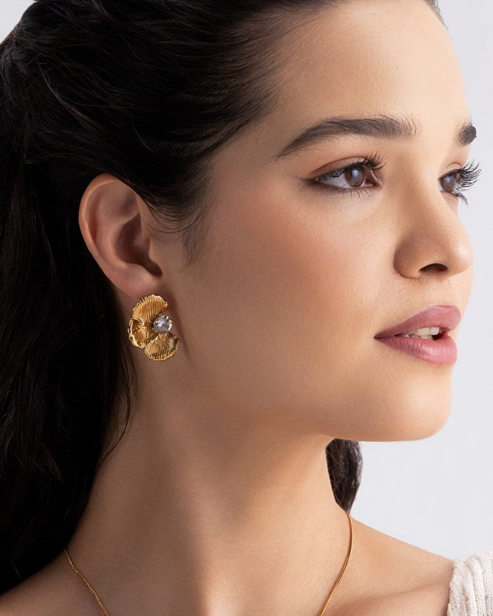 Woman wearing gold jewelry against a plain background